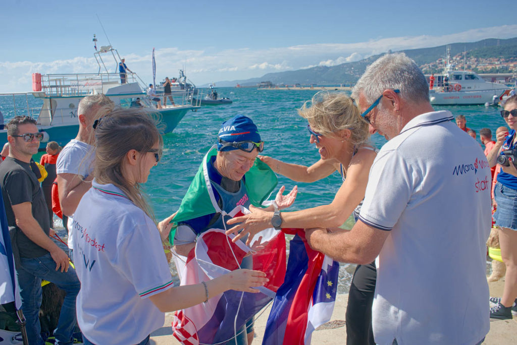 Arrivo di Silvia Boidi, nuotatrice di gran fondo, prima atleta a completare la Traversata delle Tre Nazioni (Croazia, Slovenia, Italia) nel 2024.